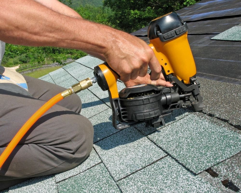 A person is using an air nailer to fix the roof.