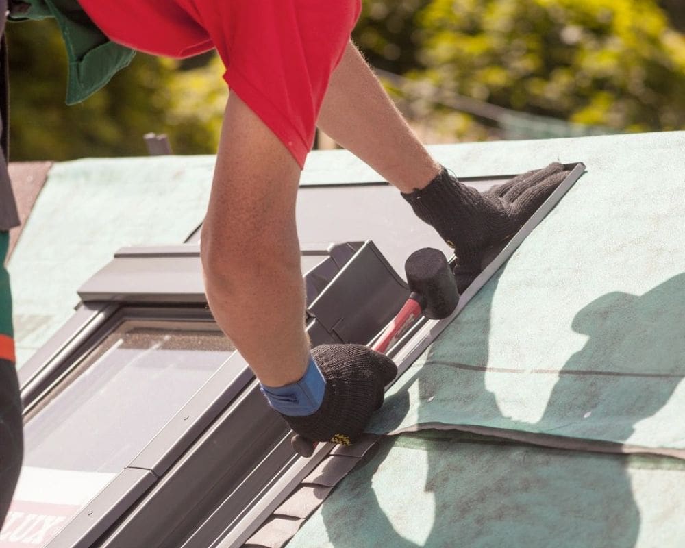 A person on top of a roof with gloves.