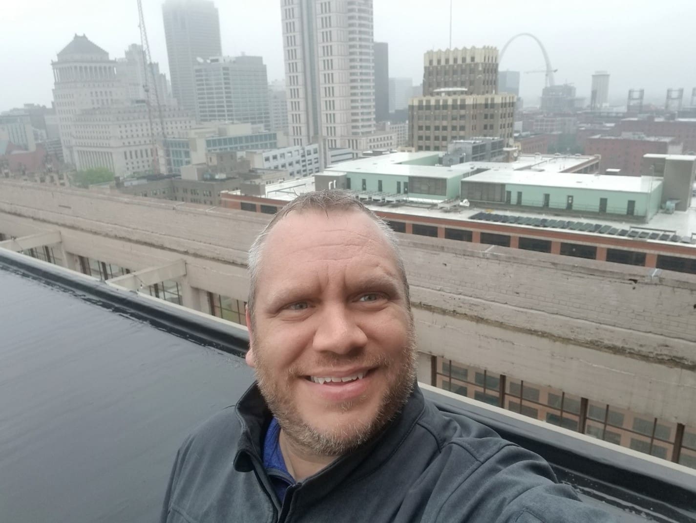 A man taking a selfie in front of the city skyline.